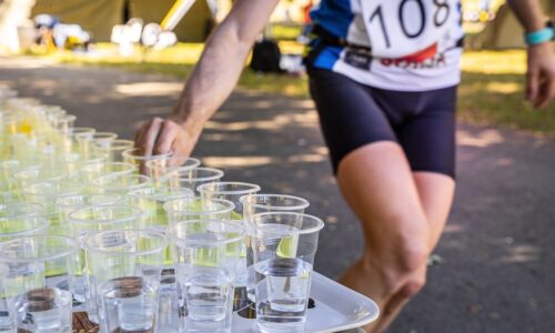 Runner,With,Race,Number,Grabbing,Plastic,Cup,With,Water,At